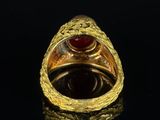 a close up of a gold ring with a red stone in it