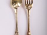 two spoons and a fork on a white surface