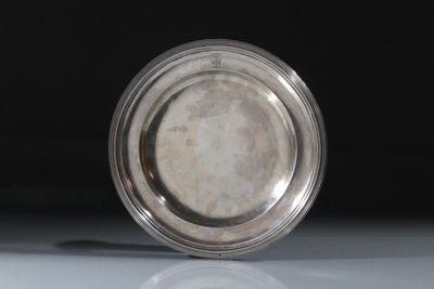une assiette en argent posée sur une table, sur fond noir