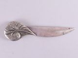 une assiette ancienne en argent, ornée d'une feuille sur un fond blanc