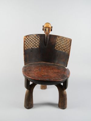 une image représentant une chaise en bois dont le dossier est orné d'un crâne
