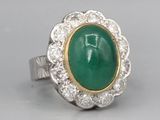a close up of a ring with a green stone surrounded by diamonds
