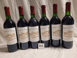 six bottles of red wine are lined up on a table