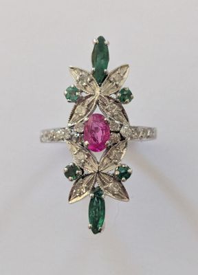 un gros plan d'une bague ornée d'une pierre rose entourée de pierres vertes et blanches