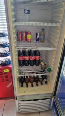 a refrigerator that has a lot of sodas and soda bottles in it