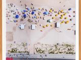 an aerial view of people on the beach with umbrellas and cars