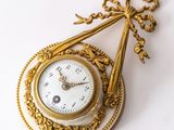 a gold clock with a chain hanging from it ' s side