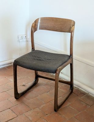 a wooden chair with a black seat on a brick floor