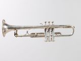 an old silver trumpet sitting on top of a white surface