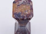 purple and orange stone ring on stand on white surface