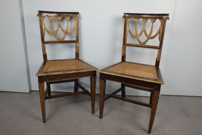 deux chaises en bois avec des assises en osier dans une pièce aux murs blancs