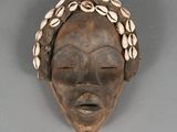 an image of a wooden mask with shells on its head