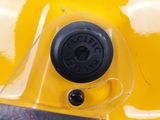a close up of a yellow helmet with a black button on it