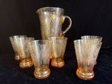 four glasses and a pitcher sitting on a black surface