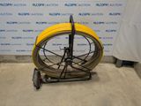 a yellow hose on a cart in front of a blue and white wall