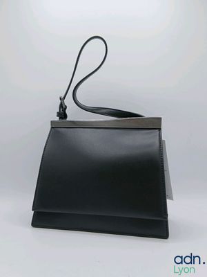 un sac à main en cuir noir muni d'une longue bandoulière, sur fond blanc