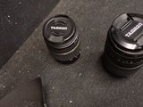 two camera lenses sitting on a table next to a cell phone