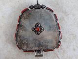 a small silver box with a red stone in it