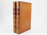 two old books sitting on top of each other on a white surface