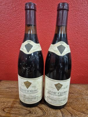two bottles of wine sitting on top of a wooden table