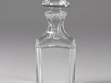 une bouteille en verre transparent avec un bouchon transparent, posée sur une surface blanche