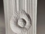 a white sculpture of a doughnut on a wooden block
