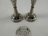 two silver candlesticks on a white surface next to a penny
