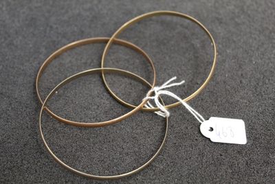 three gold bang earrings with a tag on them sitting on a black surface