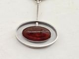 a close up of a silver necklace with a red stone on it