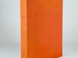 an orange book sitting on top of a white table next to a white wall