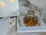 a glass bird sitting on top of a glass bottle in a box