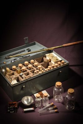 a metal box filled with glass bottles and a wooden stick