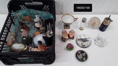 un panier noir rempli d'objets divers posé sur une table blanche