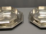 deux plats en métal argenté posés sur une table devant un fond blanc