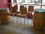 four chairs and a table in a room with a lot of wine barrels