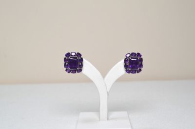 a close up of a pair of purple earrings on a white stand