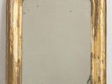 gold framed mirror hanging on a wall in a white room
