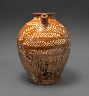un vase marron orné de motifs sur un fond gris