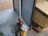 un aspirateur posé par terre à côté d'une étagère