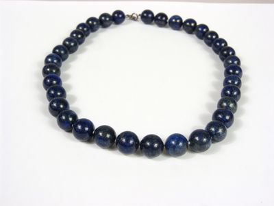 un gros plan d'un collier de perles bleues posé sur une surface blanche