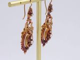 earrings on a gold plate stand with a white background
