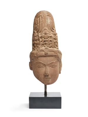 une tête de femme en pierre, coiffée d'une parure, posée sur un socle