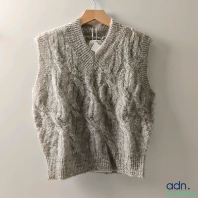 Le pull est suspendu à un cintre accroché au mur.