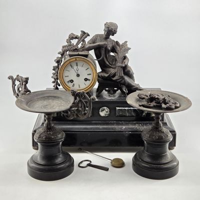 a statue of a woman sitting on a table with a clock on it