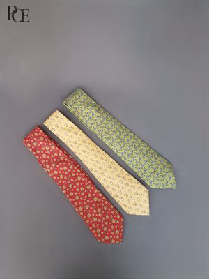 trois cravates de couleurs différentes posées sur une surface grise, sur fond noir