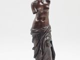 une statue antique en bronze représentant une femme debout sur un socle en marbre