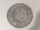 a silver plate with a design on it on a white surface
