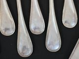 six spoons and a knife on a black table