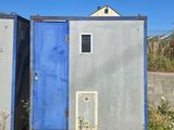 two portable toilets sitting in a field next to each other