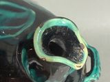 a figurine of a black and blue fish with a green eye